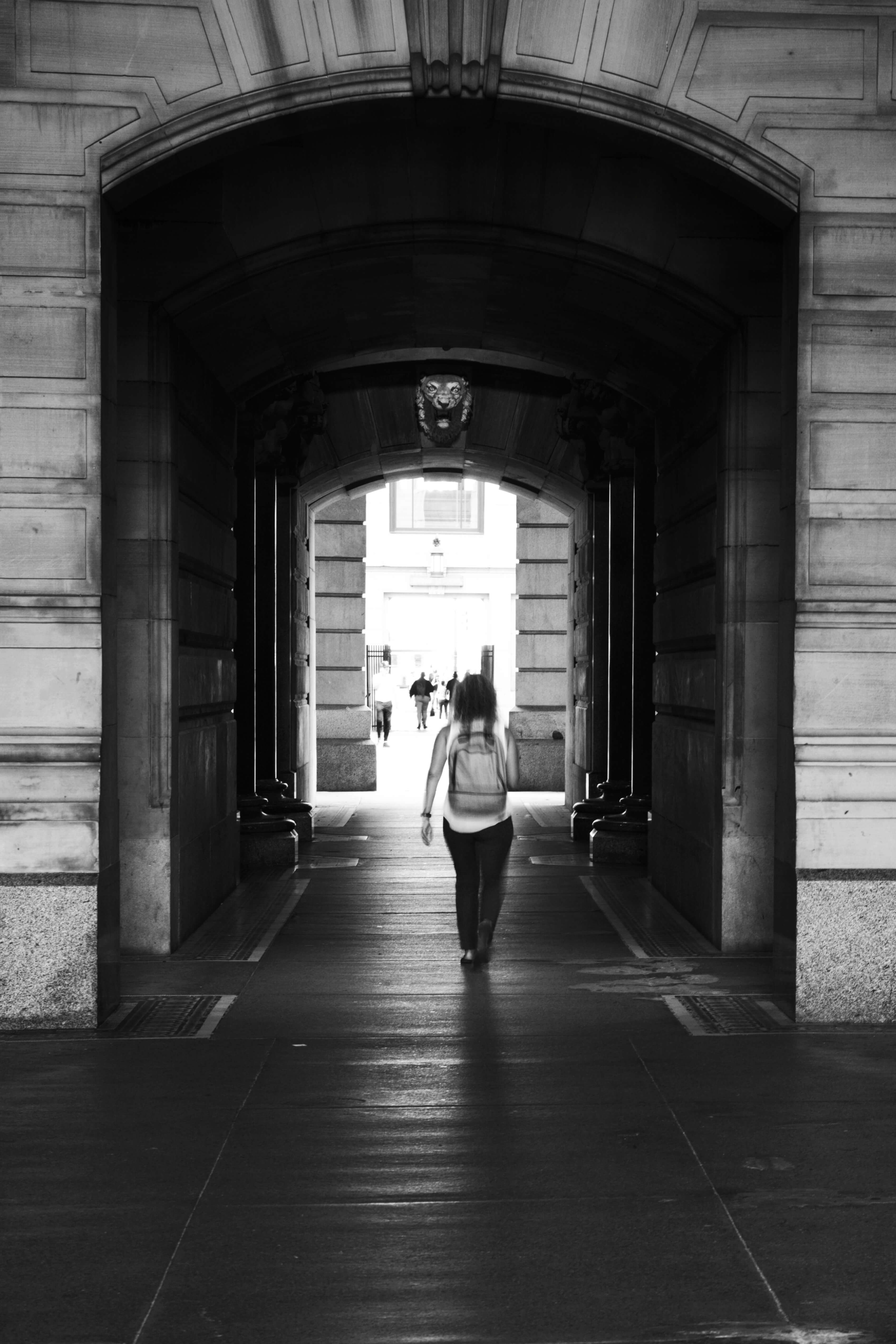 Black and White street scene photo of a girl walking through a tunnel